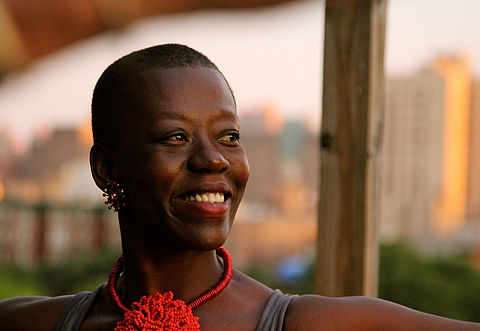 Headshot of Carmen pictured looking off to the right of the camera, wearing a red necklace with a large knotted pendant of beads