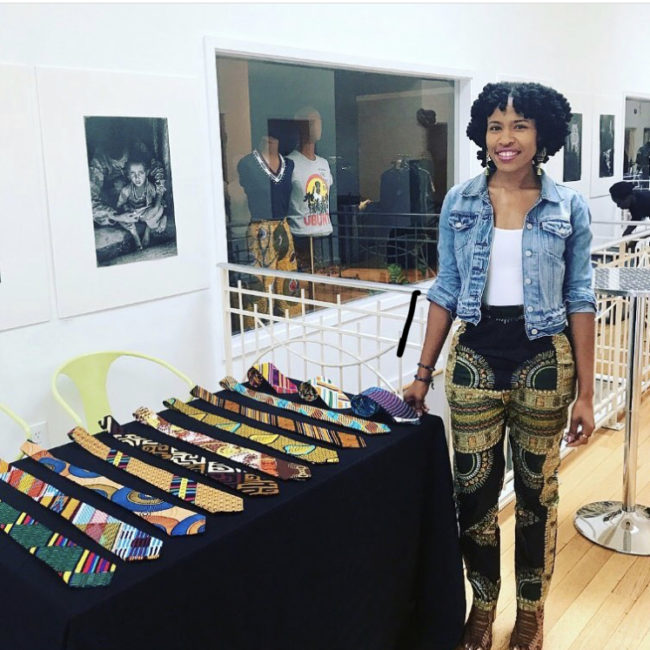 Tevia Johnson standing next to a table of neckties that she designed