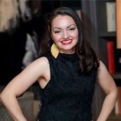 Headshot of Amanda standing in a black dress with her hands on her hips